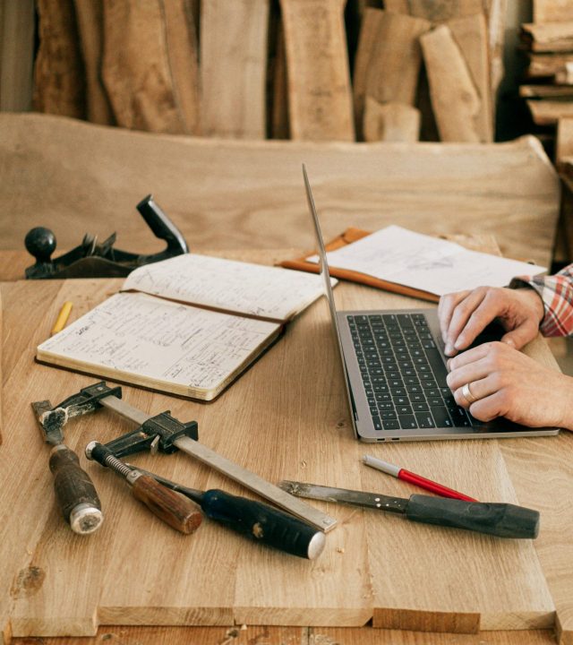 Person Using Macbook Pro on Brown Wooden Table